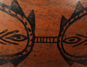 Tesuque Black-on-red pottery is fashioned in the same manner as polychrome wares. Clay, temper, paste, and construction do not differ. The difference arises when a red slip is wiped on the vessel in lieu of a cream slip.   The underside of the vessel is concave, the vessel body is rounded in the best tradition of Tewa vessels, and the design is sparse, all of which point to a date of origin of circa 1880. The light tan paste at the lower third of the vessel exhibits the bumpiness that is a trademark of Tesuque. A red band at the upper end of the tan paste divides the design area from the underbody. Double framing lines above this red band, at the shoulder, and just below the rim serve to isolate the two design areas.   The mirrored C-like design with eye-like elements and typical chevron elements cleverly conceals two Avanyu (Water Serpents) with their heads pointing down.   The inner rim of the jar is designed to support a lid. It was not unusual at Tesuque for the potters to make lidded jars. Most lids have been lost or broken. Fortunately the lid for this jar is still here, missing only the knob.