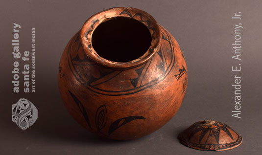 This rare and historic Tesuque Pueblo pottery vessel has an inner rim designed to support a lid. It was not unusual at Tesuque for the potters to make lidded jars. Most lids have been lost or broken. Fortunately, the lid for this jar is still here, missing only the knob. 