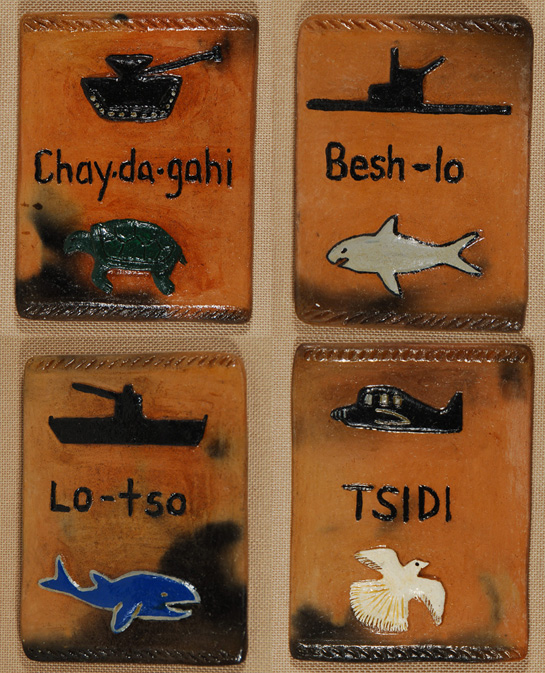 Everyone is familiar with the famous Navajo men who are known as the Navajo Code Talkers of World War II.  It was they who came up with Navajo words to substitute for naval terms and it was their ingenious use of their Navajo language that confounded the Japanese who were never able to break the code.   Elizabeth Manygoats made a set of four pottery tiles in 2005 illustrating four Navajo words and the naval words for which they substituted.  The Navajo word for whale was used for a ship, the word for shark was used for submarine, the word for turtle was used for tank, and the word for bird was used for airplane.    According to Chuck and Jan Rosenak in their book Navajo Folk Art: The People Speak, Betty Manygoats has 10 children—nine daughters and a son—many of whom are making pottery in a style similar to hers. The Rosenaks said that Manygoats was not prolific at the time of their book (1994).    The pottery tiles are mounted on fabric and framed together in a wood frame.    Condition:  original condition Provenance: from the collection of Chuck and Jan Rosenak, renowned collectors and authors of Navajo folk art.  Recommended Reading:  Navajo Folk Art: The People Speak by Chuck and Jan Rosenak.