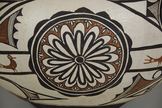 The interior of the neck of this large magnificent jar is painted black with a narrow band that is left in the matte state, not polished.  It has been noticed that jars with narrow black bands inside the rim tend to be earlier than jars with wider bands.  This is a distinctive trait of Zuni Polychrome jars starting around 1870.   The bottom area of the jar is painted the traditional black that was transitioned from the previous red underbodies starting as early as 1850 and approaching completion around the late 1890s.   The predominately rounded shape of the jar is typical of Zuni Polychrome jars of the 1870-1880 periods.  At the same time, the strong puki flexure that existed in the Kiapkwa periods is noticeably lessened on this jar but is still evident to the touch, something noted starting around 1870.    The design layout on this jar is typical of that which began in the 1870s, which is inclusion of a beautifully executed neck design with the main body design being divided horizontally by a band of birds encircling the mid-body of the jar.  The previous use of a vertical rectangular design being used as dividing the mid-body was replaced by a beautifully large rosette or medallion at this time.  These rosettes appeared around 1870.  They have been attributed to Spanish rosettes carved into furniture or to the sunflower painting on the Zuni Salimopiya Katsina face.   The main body design features large capped spirals above and below the band of small red birds that originated in the pre-1850 periods but continues even to today. They have sometimes been called volute elements.   Based on information above, it is determined that this magnificent jar was made in the period around 1880, possibly as early as the 1870s.   The information presented here is derived from the inclusive 600-page book published in 2008 exclusively on the pottery of Zuni Pueblo by Dwight Lanmon and Francis Harlow.  This is a comprehensive study of Zuni pottery and is an invaluable research resource.  It is from such research that it is now easier to estimate the date a specific vessel was made.   Condition:  When the jar arrived at Adobe Gallery, we noticed two hairline cracks from the rim running vertically down the body of the vessel on opposing sides.  We had the cracks professionally stabilized to prevent further damage.  There is no other damage or repair to our knowledge.