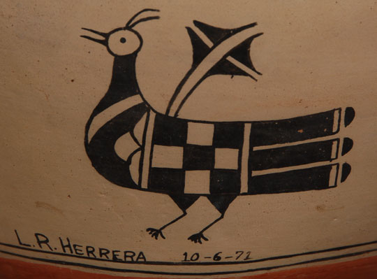 Sometimes we have to take an educated guess as to the age of a painting or pottery item we acquire, but Laurencita Herrera prevented us doing so on this olla as she not only signed her name but put the date 10-6-71 on the sidewall.  Laurencita was the mother of Seferina Ortiz and Mary Frances Herrera along with seven other children.  These two sisters are well known to pottery collectors.  The design on the olla is divided into a continuous repeated rim design and two panels of design on the body.  The design elements around the rim are stacked clouds.  On the main body, the feature is a pair of exquisitely decorated proud standing birds on opposing sides of the jar.  The panels dividing the two birds are elaborate checkerboard bars with feathers and clouds supporting them at the top and cactus plants at the base.  Condition:  the jar is in very good condition with only very minor abrasions to the slip.  Provenance:  from the collection of Katherine H. Rust 