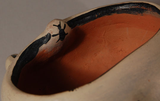 Figurine pottery has always been a tradition at Cochiti. Long before other pueblos were producing figurative pottery, Cochiti was in the forefront. Frogs seem to have been a favorite by a number of potters there.  This frog with a very wide open mouth is highly decorated and best viewed from the rear.  There is a bug on its tongue, rain clouds with lightning and rain on its sides, and raised bumps on it back.  The artist, Juanita Arquero, was a sister of Cochiti drum maker Fred Cordero, the husband of Helen Cordero.  It was Juanita Arquero who encouraged Helen Cordero to make pottery as a means of earning extra income.  The two potters would sell their wares in Albuquerque’s Old Town and at Pueblo feast day activities.  They later taught pottery classes together at a school in Bernalillo, New Mexico.    Condition:  the figurine is in original condition.  Provenance: from the collection of Katherine H. Rust  Recommended Reading: The Pueblo Storyteller by Barbara A. Babcock 