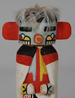 “The Talavai Kachina formerly appeared in pairs on the rooftops and sang songs, waking the people in the village. During the day they would dance with the other kachinas that they led and prompted in the singing. This role is no longer used in any of the villages. They still appear with the other Kachinas in the Powamu Ceremony and are most often standing in a set to one side of the main movement of the procession.” Wright  Based on the paint used, this doll probably dates to the 1940s decade.  It has been mounted on a black stand which could be removed if one wished to hang the doll.  Condition:  the carving is in excellent condition.  The fan of feathers normally behind the mask has been removed because the feathers were in violation of Federal Regulations regarding feathers of migratory birds.  Provenance: from a California gentleman  Referenced Book: Kachinas: a Hopi Artist’s Documentary by Barton Wright 