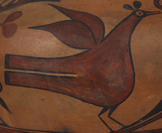 Realistic birds on Zia pottery appeared around 1820 and their use has continued to today. They became much more in evidence by 1870.  The birds on this jar are typical of Zia birds of the time.  They have wings that are separate from the body that look similar to leaves.  They have short legs, red bodies outlined in black, split tail feathers and black heads.  The pupil is a small dot in a round eye and the beak is split as if the mouth is partially open.  The lobes on the head that appear to be ears actually represent feathers.  The unusual aspect of the decoration, and the most spectacular design element of any Zia jar,  is the mirror-image design that separates the bird elements.  The triangular elements, one of which is suspended from the upper framing line and the other resting on the lower framing line, have hooked ends that could represent the beak of a bird such as a parrot.   The two pair of red balloon-like elements represents feathers.  There is a wide red band underneath the framing lines.  Two of the four birds have wings that overlap and two have wings that are separated.  The ones with separated wings have fringe-like lines at the edge of the feathers.  Their tail feathers have pointed ends whereas the other two birds have rectangular tails.    Overall, the jar is spectacularly beautiful. It dates to circa 1890s and has a patina consistent with such an age.  It’s a beautiful jar of a size that is impressive.  Condition: excellent condition  Provenance: from a gentleman in Colorado  Recommended Reading:  The Pottery of Zia Pueblo by Harlow & Lanmon 