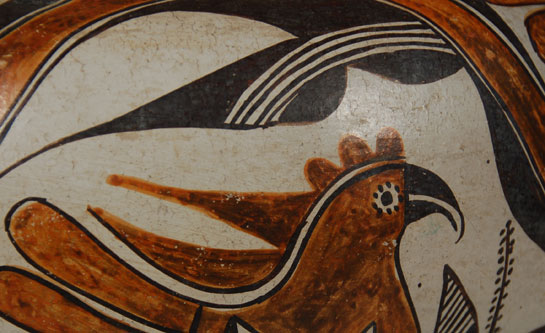 Pueblo pottery had not shown any strong design influence from non-indigenous sources until the nineteenth century. It was in the mid-1800s that changes in designs became noticeable. It has been stated that some of the ornate designs on Acoma pottery—such as the parrot, rainbow, and berries—might have been influenced from Pennsylvania Dutch designs that the pueblo inhabitants could have seen on fabrics or furniture of Pennsylvania Dutch origin. These designs reached their maturity by the end of the 1800s and have been in continuous use since.  Birds on pueblo pottery have been popular since prehistoric times. Their representation in the earlier times was more abstract than representational. They reached their peak with Sikyatki Polychrome from the Hopi in the period 1375 to 1650. The representational parrot design seen on Acoma pottery such as this jar has stayed essentially the same since its inception in the mid-1800s. The bird is often perched on a branch and eating berries. It has a curved beak typical of parrots. Quite often there is a design—circular or diamond—on the breast of the bird and a D-shaped element at the base of the tail.  This is an exceptionally fine example of an Acoma Pueblo polychrome olla of this style.  It probably dates from the first third of the 20th century. It was formed in native clay with ground pottery shard temper and exhibits a rag-wiped white slip, orange neck interior, and orange-slipped underbody with concave base, typical of Acoma pottery. The high point of maximum diameter, design elements, execution and a shorter neck are indicative of vessels of this time period.  The artist used the full field to express the single artistic concept rather than divide the design area into sections. The design features large, bold whimsical parrots over and under an undulating rainbow. Each parrot is perched onto a plant stem as if eating berries from the plant. The parrots each have a diamond on its breast and a D-shaped element at its tail.  The rim top is black and the framing lines are worked in vegetal black.  This design is the most sought after in Acoma ceramics. It is the style every collector cherishes.  Condition:  the jar is in very good condition.  Examination with UV light does not show any repairs or restoration or paint touch-up.  Everything is original.  There is minor rim wear from prior use but it is not significant. Overall, it is a real fine jar. Provenance:  from the collection of a New Mexico family Recommended Reading:  Acoma and Laguna Pottery by Rick Dillingham 