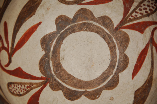  One can almost feel the peacefulness at sunset as the sky turns from a fiery red to yellow. Rarely do we see Zuni bowls with a red underbody. Since the late-1800s, most potters have used black. According to Batkin, “Zuni Polychrome vessels retained the red rim and underbody slip of Ashiwi Polychrome until the late eighteenth or early nineteenth century, when it was replaced by dark brown paint…” ¹  The paste materials are typically Zuni; white and chunky in texture with the centuries old temper material of ground pottery shards. The use of old shards for temper evidences the regard of the pueblo peoples for the old works made by their predecessors. To add these remnants to the new work is a sign of respect.  The rim of the bowl curves inward slightly, imparting a graceful shape to what could otherwise be an uninteresting one. The interior of the rim flexes slightly, an unnecessary added feature that enhances its shape. The bowl is slipped in traditional fashion with cream-colored clay, over which is painted the designs in mineral and vegetal paints. The exterior is decorated with the traditional prayer stick design used on every Zuni bowl made in the nineteenth century. It is thought that this was a woman's way to place her prayers since women do not make prayer sticks.  The interior decoration begins with a brown rim, below which is a series of rectangles divided into triangles encircling the bowl that are rendered solely in brown. Below this are two wide parallel framing lines with a very distinctive ceremonial break. Two Zuni volute design elements in brown paint fill the interior of the bowl. These are attached to two corn-like elements, executed in red without outlining. The bottom has a double circle, one of which is cloud-like, outlining an otherwise undecorated center. On the exterior of the bowl is written the numbers 39975 in beautiful hand Script. This is most certainly an acquisition number placed there by one of the earlier expeditions to Zuni.  1. Reference: Pottery of the Pueblos of New Mexico: 1700-1940.  Jonathan Batkin. The Taylor Museum of the Colorado Springs Fine Arts Center. 1987.  UPDATE INFORMATION: Dwight Lanmon so kindly provided the following information. The numbers 39975 are BAE accession numbers indicating that Stevenson collected the bowl in 1879 on the Powell Expedition. He confirmed with the Smithsonian that the numbers 475 are Stevenson's field numbers.  