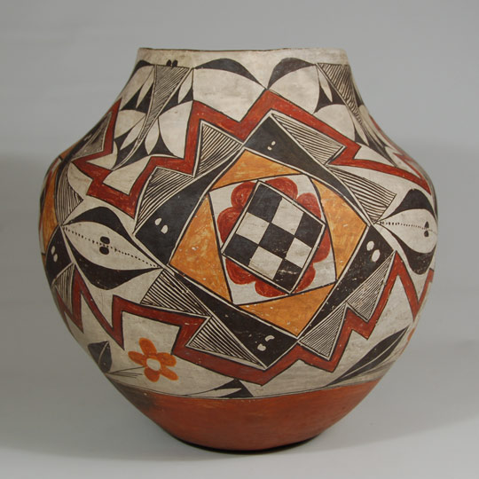 A very old paper note inside this jar is labeled Laguna and we tend to agree that it certainly could be a jar from Laguna Pueblo, circa 1880s.  It is a large jar with a magnificent design from just above the base to the rim, without division panels.  It is a four-color polychrome and a very visual one.  The dark red zigzag lines (two of them) encircle the jar and act as outlines for the major design of the mid-body.   There are four small diamonds filled with black and white checkerboard elements, these in turn are outlined with red petals of the nature of a flower, both of which are then outlined in a white box with black outlining.  Another diamond of orange color outlined in black lines encompasses these other elements.  This whole four-part design is surrounded by black triangles on all four sides, each of which has a pair of white "eyes."  These black triangles, in turn, are surrounded by paired triangles filled with parallel fine lines.   Interestingly, one of the black triangles with "eyes" is not black, but is white with a black figure 8 in lieu of "eyes" or perhaps the 8 is a set of eyes. Knowingly placing the black 8 in the white triangle is the potter's sign to us that leaving this one white was intentional, not an accidental oversight.   There are four of the multi-layered triangular and diamond elements that form the main design of the jar and they are each sandwiched between the dark red zigzag lines and connected to each other by a pair of quarter-moon black curves split by black dots.  There are flowers and other fine-line and black triangle designs throughout the whole pot.  It is truly an amazing jar.   Condition:  UV light examination reveals that there has been some conservation at the rim.  It appears that two triangular-shaped pieces of the rim were broken off and replaced, without plaster fill.  A lateral crack appears to have had the same conservation, without plaster.  There is some abrasion to the design but nothing exceptional. Provenance: from a family in Santa Fe, one of whom is the author of a new book Southwest Art Defined: An Illustrated Guide Recommended Reading: Acoma and Laguna Pottery by Rick Dillingham