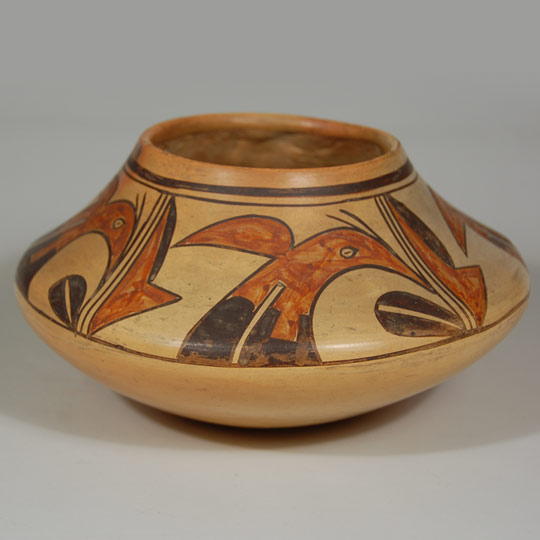 This visually charming Hopi-Tewa jar demonstrates in style and technique all the hallmarks of a circa 1920s product. The shape is derived from the bulbous shouldered saucer shaped jars common to the prehistoric Sikyatki pottery tradition of the 15th and 16th centuries. The vessel has a conical up-thrusting neck gracefully projecting from the jar's body without seam or flexure.   The design composition is perfectly complementary to the sculptural form of the vessel. The heavy unbroken black encircling upper body band separates the neck of the jar from its mid body. Interestingly, a thin black framing line just below the wide framing line of the neck does feature a ceremonial line break.  The framing line at the mid body does not have a ceremonial line break.   The avian designs and geometric elements point to the aesthetic of an outstanding potter and painter, whose identity will remain a mystery.   The jar was fired in a coal-burning atmosphere, contributing the ivory toned color to the jar's surface and the polished inner lip of the rim. Such jars were featured prominently at the Fred Harvey Hopi House at the Grand Canyon.   Condition: very good condition Provenance: from the collection of Dr. Allan Cooke, co-author of the book Canvas of Clay: Seven Centuries of Hopi Ceramic Art who purchased it from Santa Fe dealer and collector Richard M. Howard in 1997. Recommended Reading:  Canvas of Clay: Seven Centuries of Hopi Ceramic Art by Edwin L. Wade and Allan R. Cooke