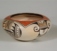 Helen Naha (Feather Woman) and Joy Navasie (Frog Woman) were sisters-in-law.  Helen Naha married Joy Navasie's brother, Archie Naha. Helen was known for her stark black-on-white Hopi pottery early in her career and for exquisite polychrome pots in later times. Her hallmark is a feather.   This wonderful wide and low jar is slipped in traditional white slip, over which is painted the decoration in deep dark brown. The design is often referred to as a "bear claw." The round opening at the top of the jar has been outlined in a square orange slip which was then outlined in a pair of black lines.  The designs on the four sides of the jar are pendant from the outer black rim line.   Condition: The jar is structurally in excellent condition. There is some slip loss near the feather hallmark on the underside but nothing truly significant. Provenance: from the collection of an elderly Santa Fean Recommended Reading: Hopi-Tewa Pottery: 500 Artist Biographies by Gregory and Angie Schaaf 