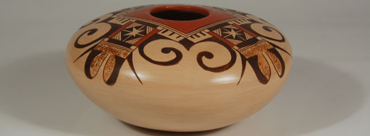 This jar by Adelle features a very traditional Nampeyo family design using a painted square around the opening and four eagle tail designs radiating from that square.  