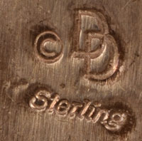 Bernard and Frances Dallasvuyaoma artistically collaborate making jewelry with each other and sign with co-joined Ds and the word Sterling.