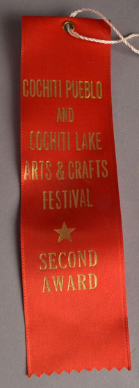 This figurine was entered in competition at the Cochiti Pueblo and Cochiti Lake Arts & Crafts Festival in October 1981 and was awarded a Second Award ribbon. 