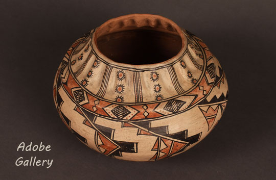 Martina embellished the traditional olla shape by adding a raised shoulder. A strong neck with vertical ribs impressed into the clay rises from the shoulder. Florentino highlighted the ribbed neck by adding patterns of vertical lines and circular forms, which alternate with each raised band of clay.