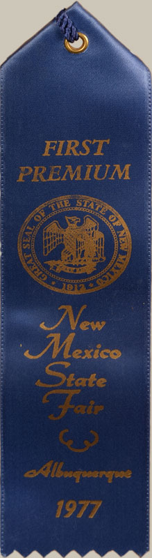 The painting dates to 1977, when it was entered in competition at the New Mexico State Fair. “Mimbres Scorpion” received the “First Premium” prize, and the blue ribbon and entry tags still hang from the back of the frame. 