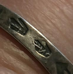 The band is stamped with an arrow just below the top of the ring and stamped with two pairs of three-pronged designs around the back of the band. One of these band designs clearly shows the letter N within the depth, possibly an indication that the ring was made from coin silver.