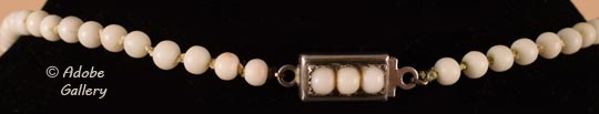 Three miniature white coral beads are attached to the silver clasp.