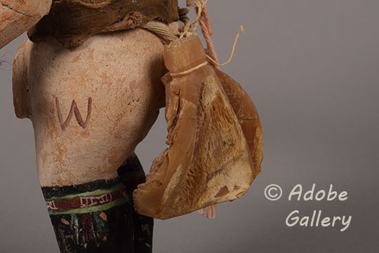 One of the most unusual features of this carving is the inclusion of three raw mineral specimens (likely petrified wood or agate) hanging from his backside. These stones are unpolished and translucent, ranging from amber to brown with visible crystalline banding. 