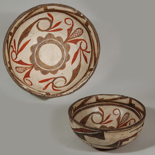 One can almost feel the peacefulness at sunset as the sky turns from a fiery red to yellow. Rarely do we see Zuni bowls with a red underbody. Since the late-1800s, most potters have used black. According to Batkin, "Zuni Polychrome vessels retained the red rim and underbody slip of Ashiwi Polychrome until the late eighteenth or early nineteenth century, when it was replaced by dark brown paint..." ¹ The paste materials are typically Zuni; white and chunky in texture with the centuries old temper material of ground pottery shards. The use of old shards for temper evidences the regard of the pueblo peoples for the old works made by their predecessors. To add these remnants to the new work is a sign of respect. The rim of the bowl curves inward slightly, imparting a graceful shape to what could otherwise be an uninteresting one. The interior of the rim flexes slightly, an unnecessary added feature that enhances its shape. The bowl is slipped in traditional fashion with cream-colored clay, over which is painted the designs in mineral and vegetal paints. The exterior is decorated with the traditional prayer stick design used on every Zuni bowl made in the nineteenth century. It is thought that this was a woman's way to place her prayers since women do not make prayer sticks. The interior decoration begins with a brown rim, below which is a series of rectangles divided into triangles encircling the bowl that are rendered solely in brown. Below this are two wide parallel framing lines with a very distinctive ceremonial break. Two Zuni volute design elements in brown paint fill the interior of the bowl. These are attached to two corn-like elements, executed in red without outlining. The bottom has a double circle, one of which is cloud-like, outlining an otherwise undecorated center. On the exterior of the bowl is written the numbers 39975 in beautiful hand Script. This is most certainly an acquisition number placed there by one of the earlier expeditions to Zuni. 1. Reference: Pottery of the Pueblos of New Mexico: 1700-1940.  Jonathan Batkin. The Taylor Museum of the Colorado Springs Fine Arts Center. 1987. UPDATE INFORMATION: Dwight Lanmon so kindly provided the following information. The numbers 39975 are BAE accession numbers indicating that Stevenson collected the bowl in 1879 on the Powell Expedition. He confirmed with the Smithsonian that the numbers 475 are Stevenson's field numbers. 